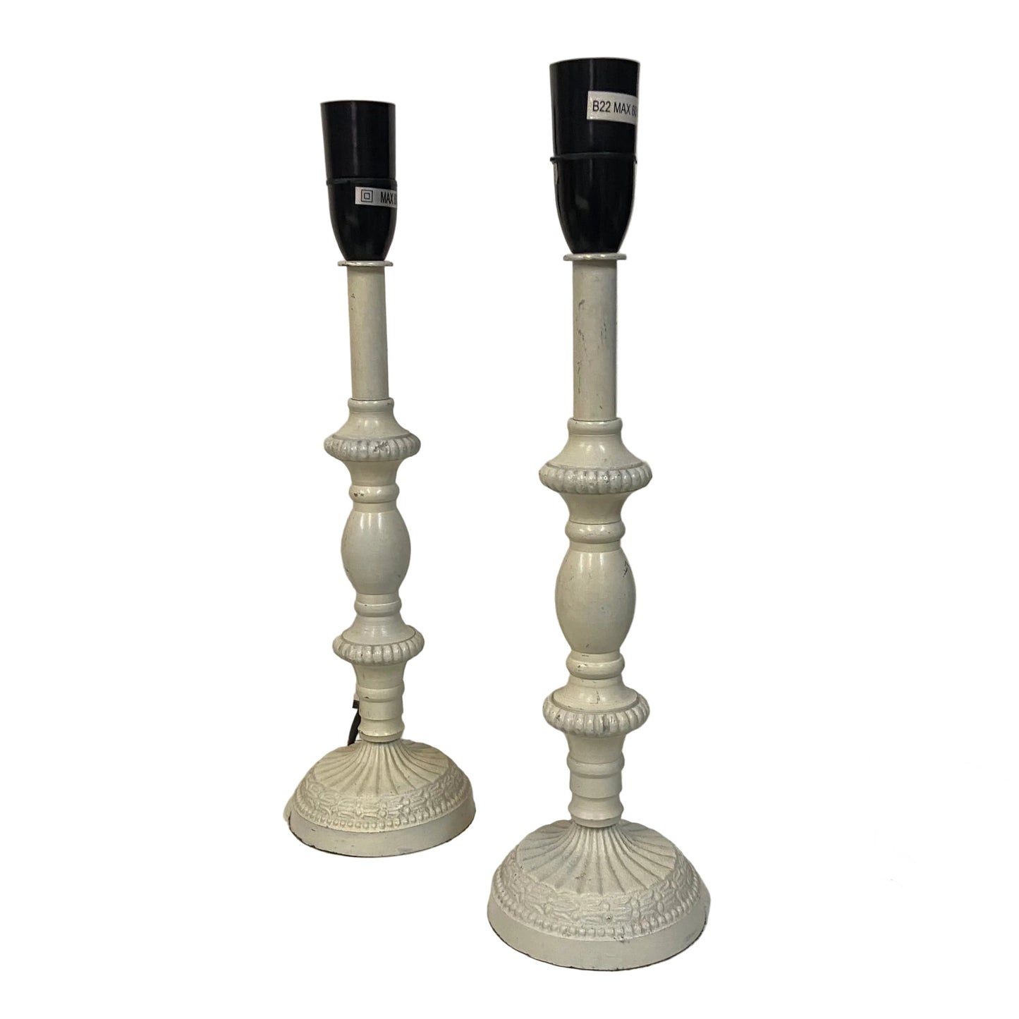 Two white candlesticks with black candle holders on a white surface.