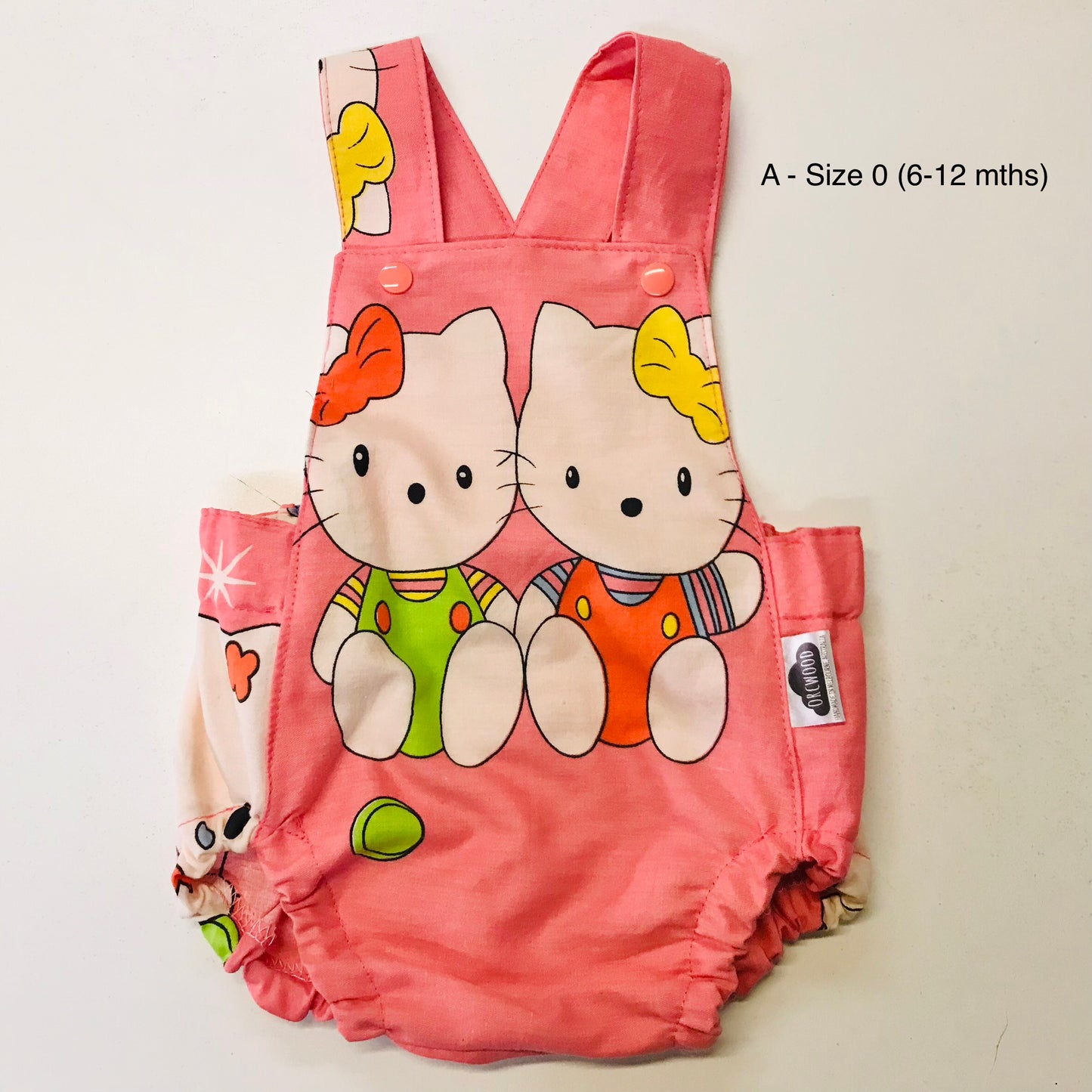 Pink baby romper with cartoon characters on a light beige background