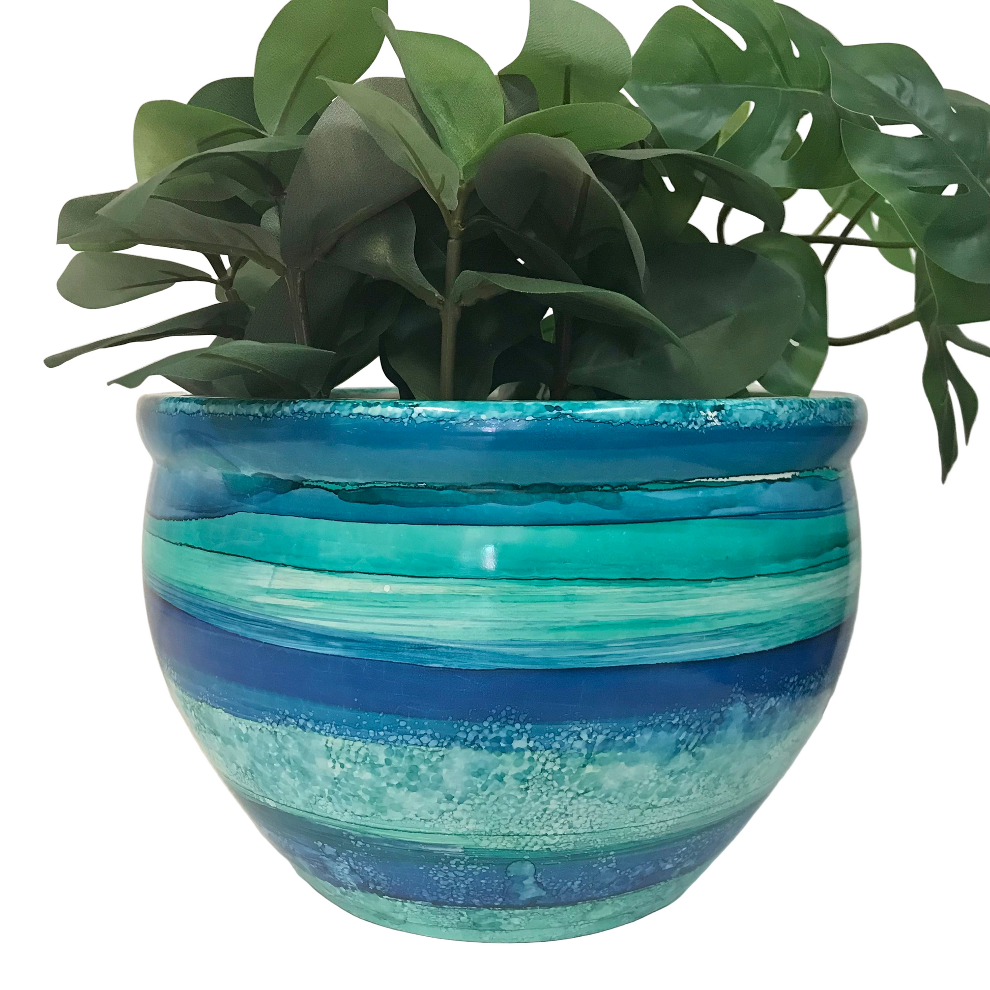 Blue and green striped planter with a plant on a white background