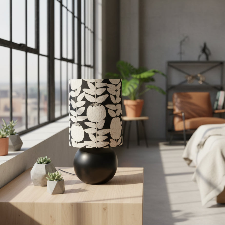 Black lamp with a patterned white lampshade on a white surface.