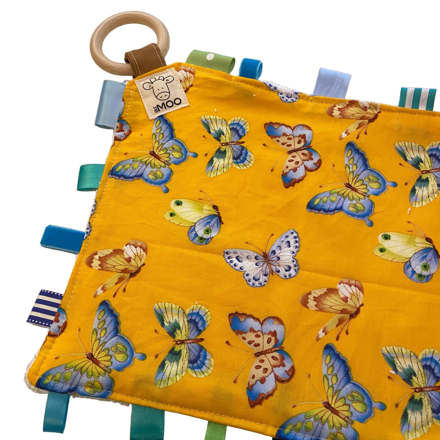 Yellow fabric taggie teething toy with butterfly patterns on a textured surface