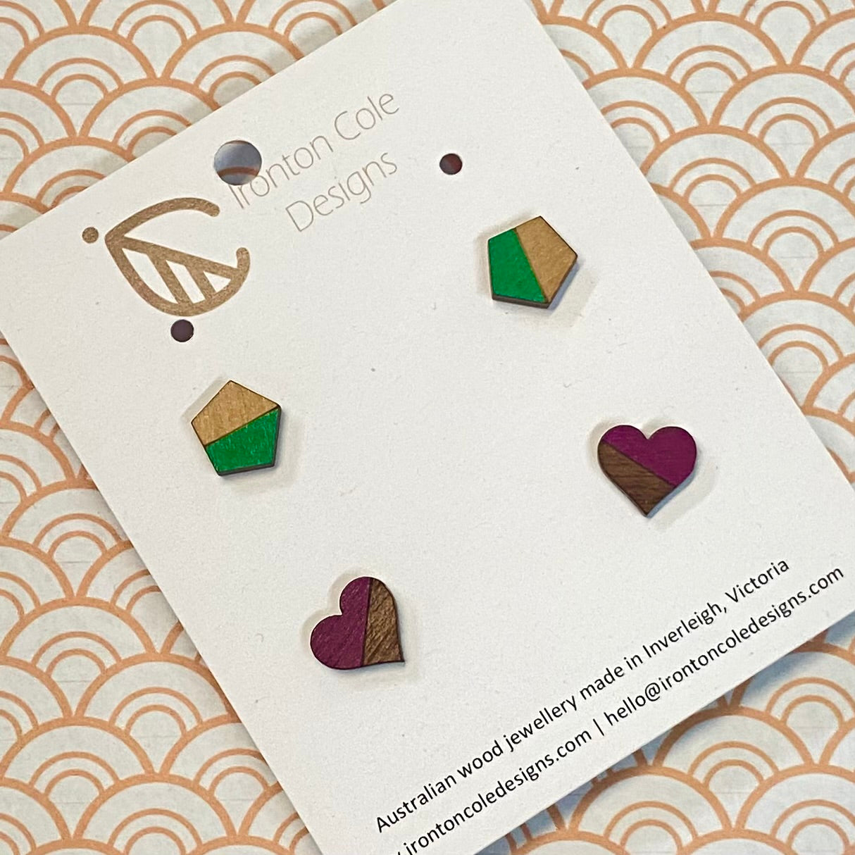 Wooden earrings on a branded card with geometric designs.