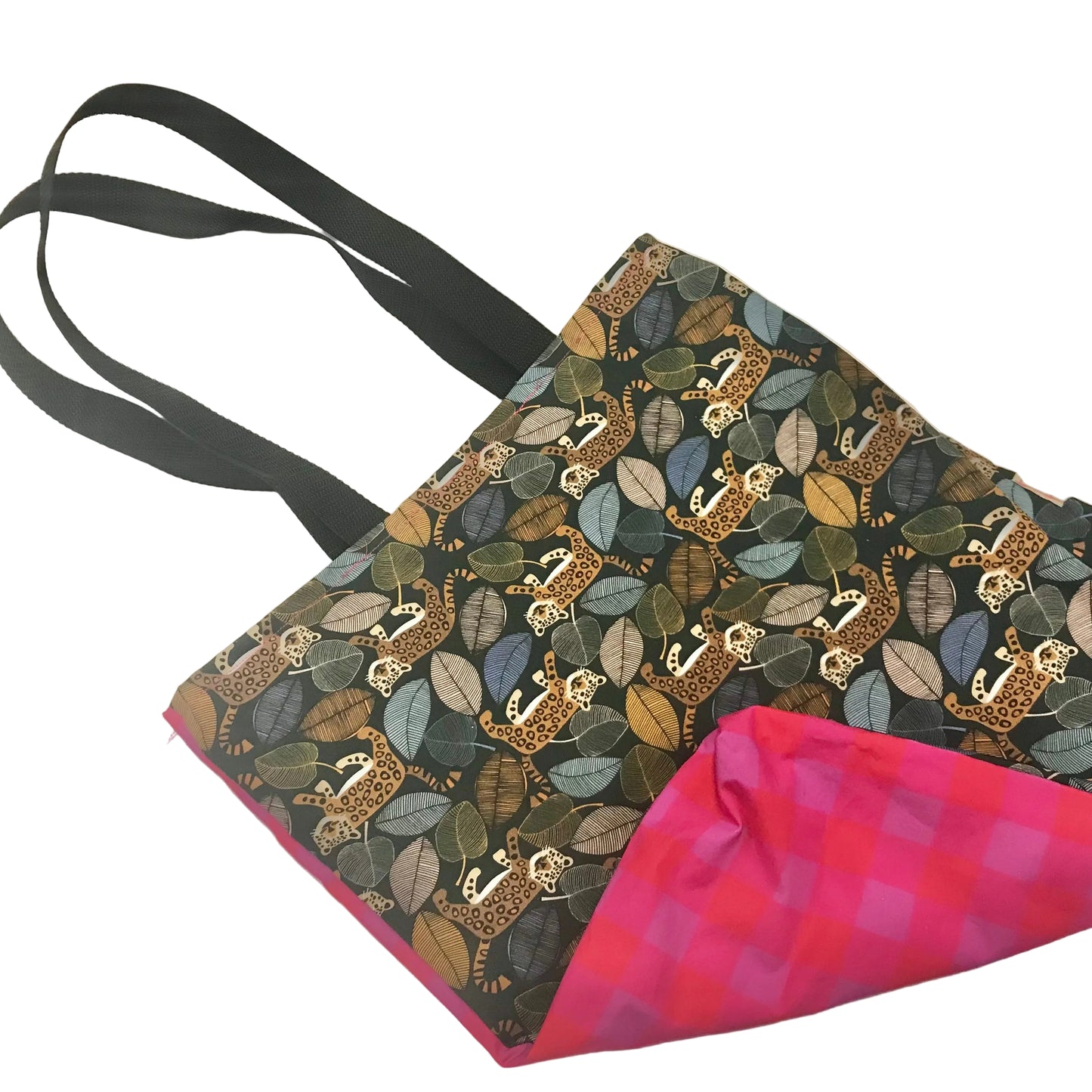 A fabric tote bag with black shoulder straps, featuring a dark patterned exterior with illustrated leopards and leaves in muted green, blue, and brown tones, and a bright pink and purple gingham lining visible at the corner.