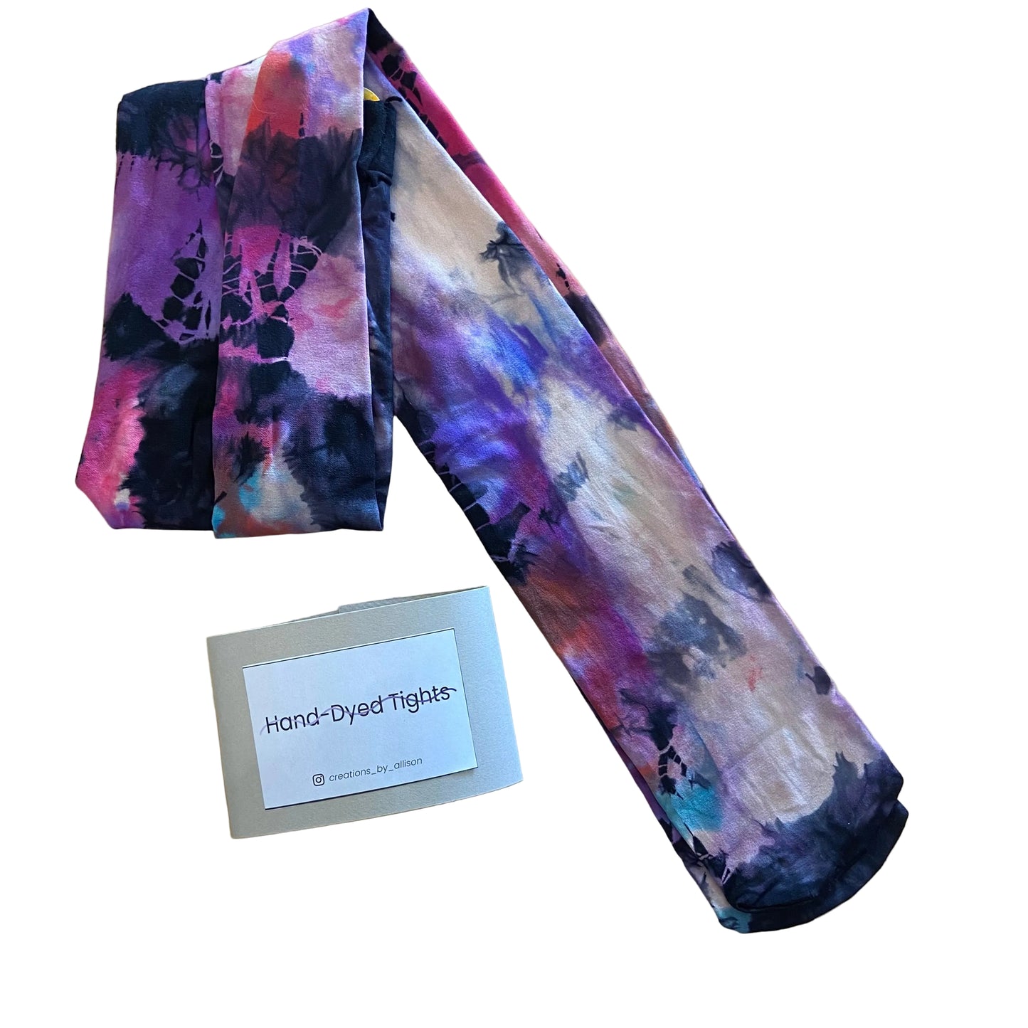 Hand-dyed tights with a tie-dye pattern on a wooden surface, accompanied by a label reading 'Hand-Dyed Tights'.