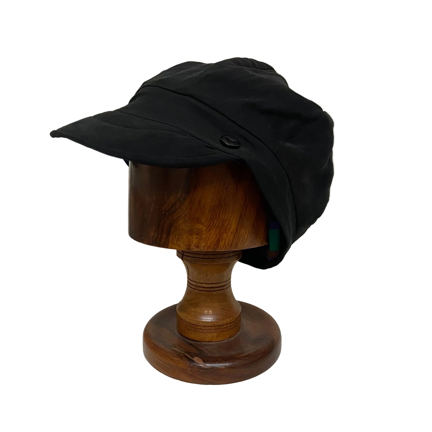 Black cap on a wooden mannequin head against a plain background