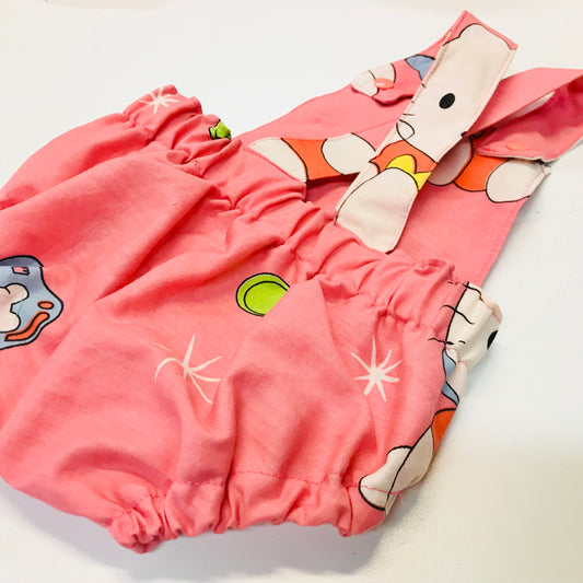 Pink baby romper with cartoon character on a white background, showing back with straps and elastic waistband