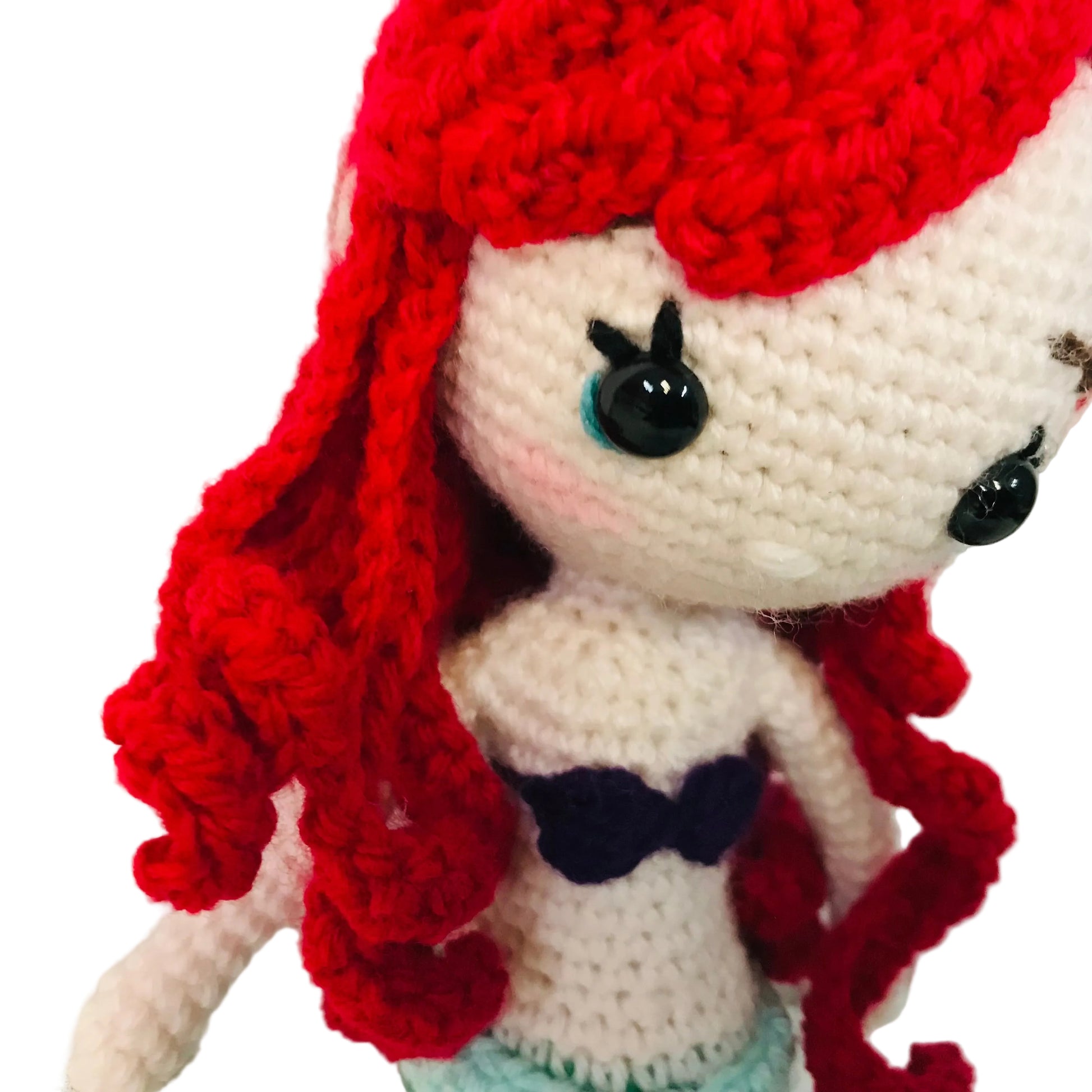 Crocheted doll with red hair and white face on a light background