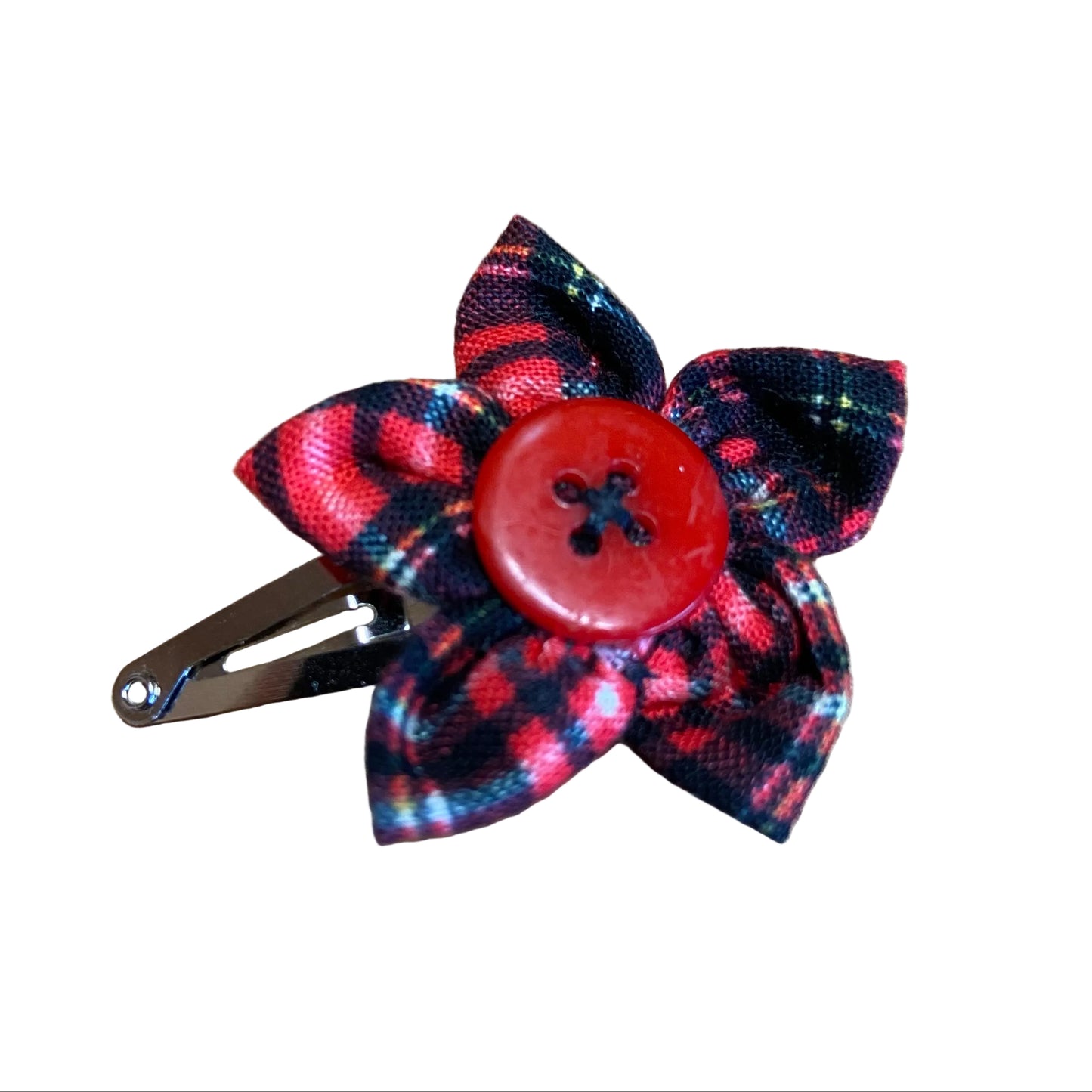 Floral hair clip with a red button center on a wooden surface