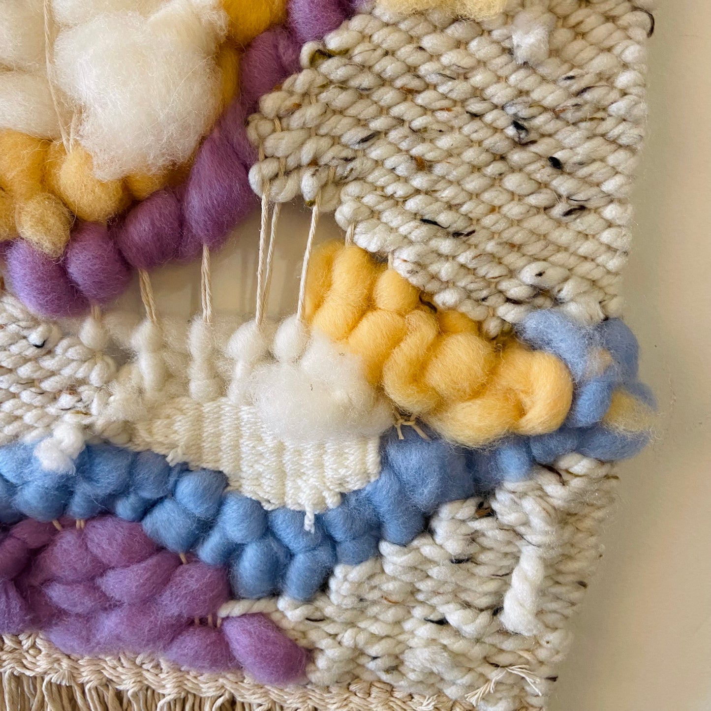Woven wall art with multicolored yarn on a neutral background