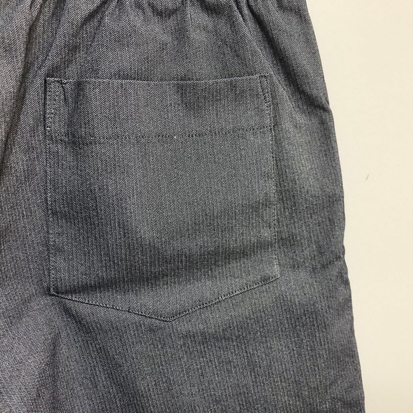 Close-up of gray pants with a pocket on a beige background