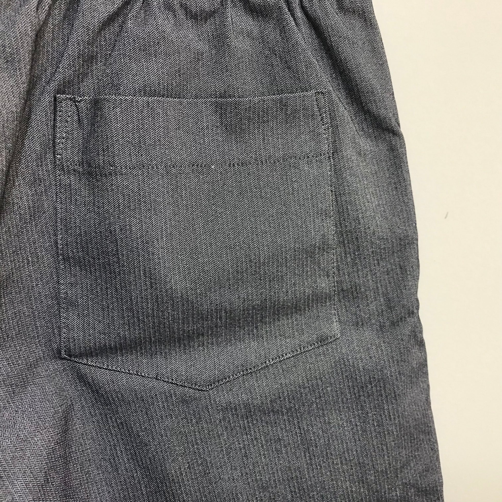 Close-up of gray pants with a pocket on a beige background