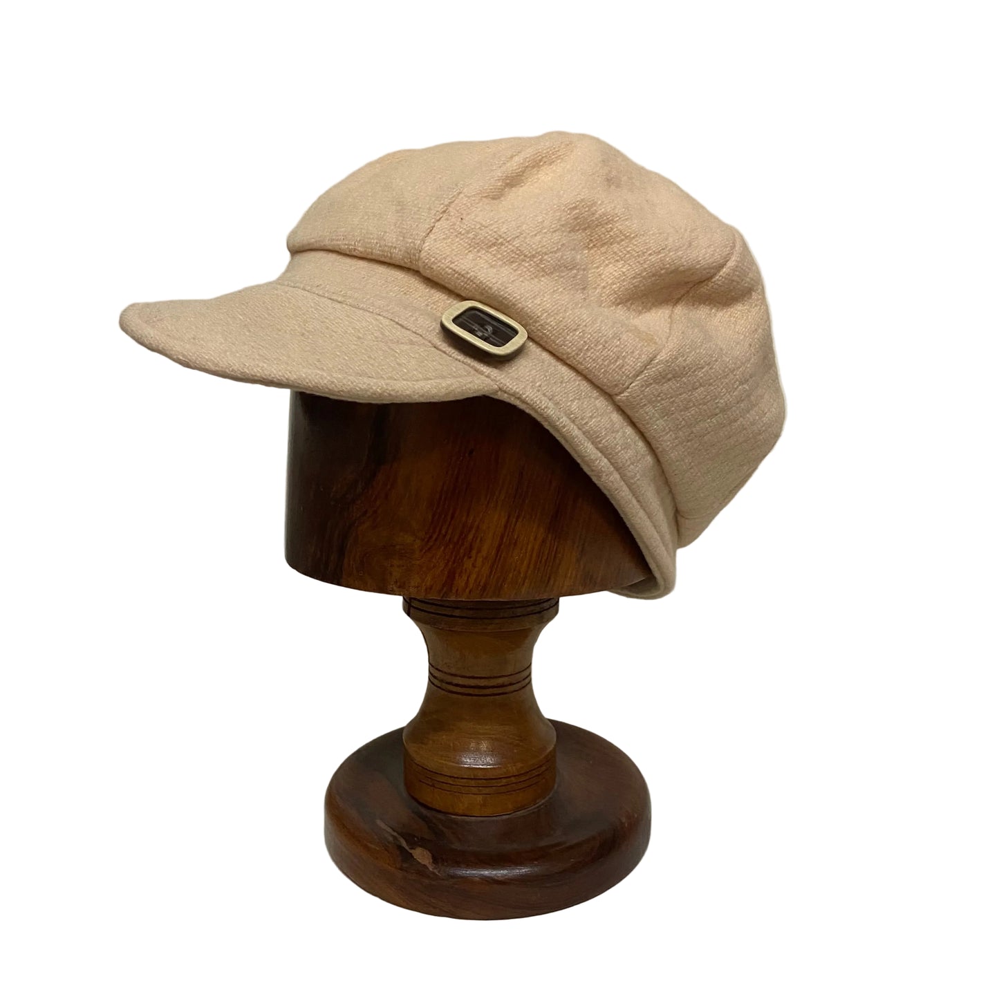 Beige cap on a wooden mannequin head against a plain wall.