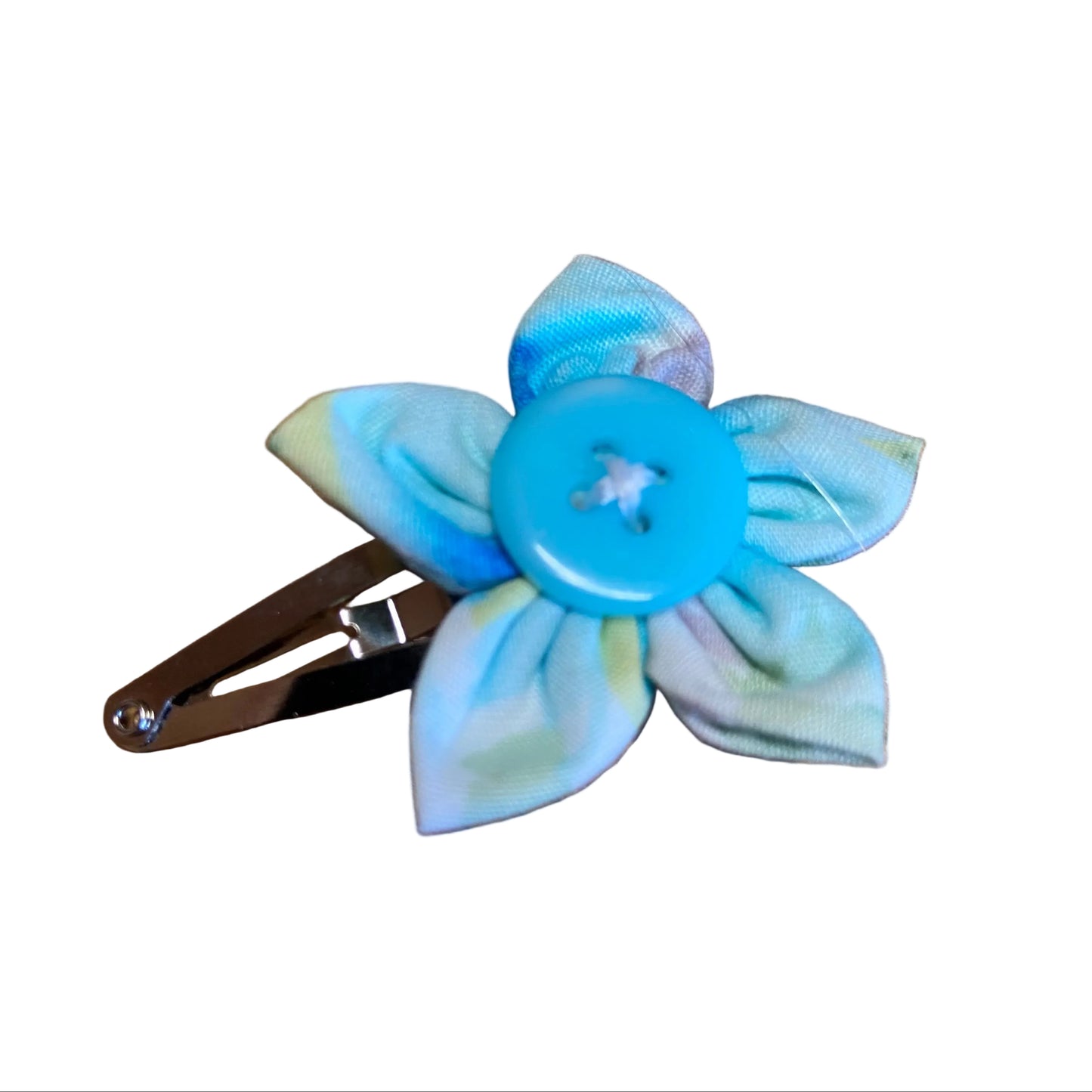 Floral hair clip with a blue button center on a wooden surface