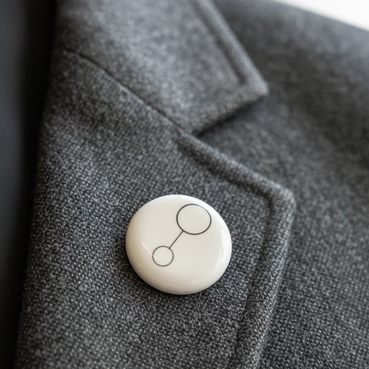 White ceramic brooch with black design Glyph on a brown textured surface