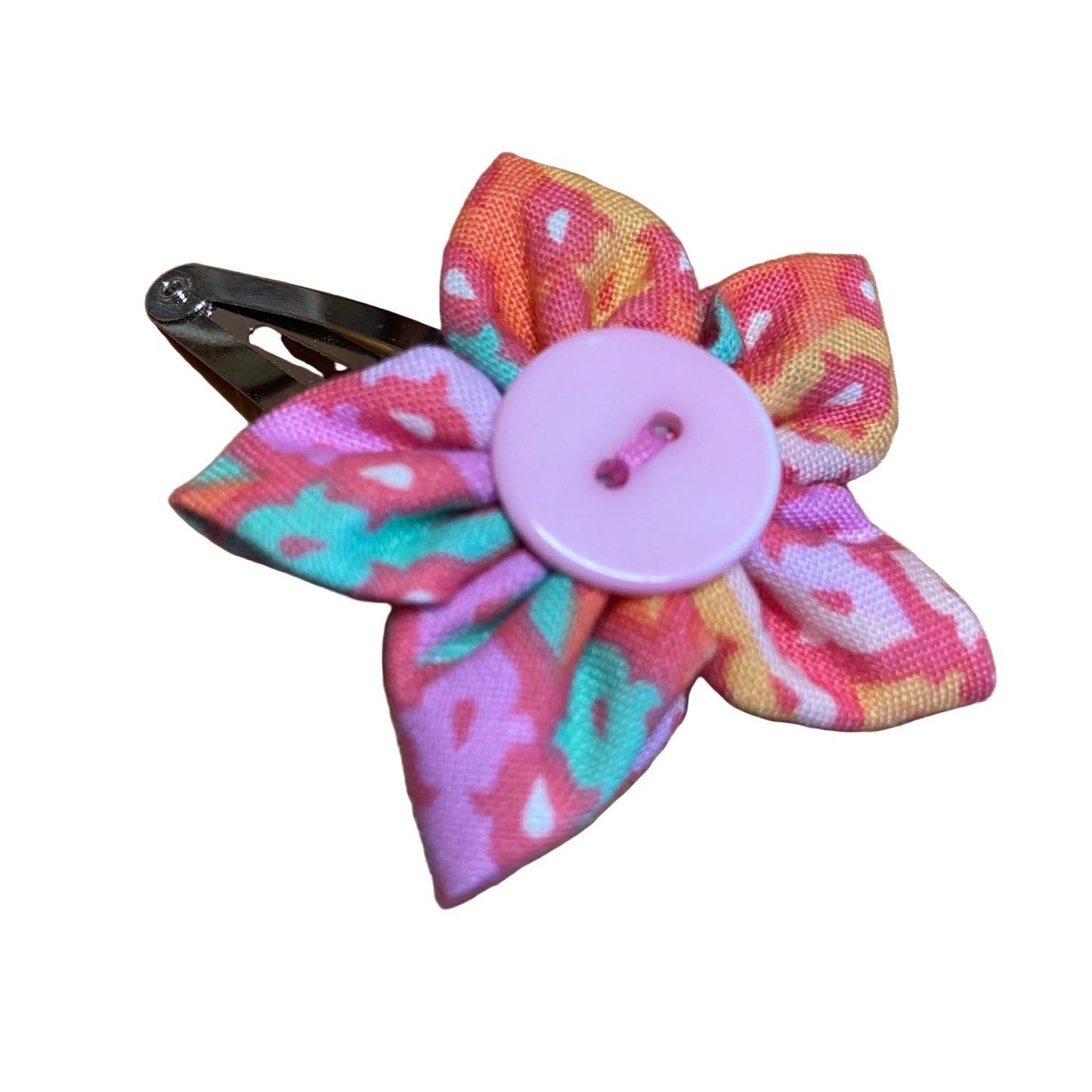 Colorful fabric flower hair clip with a pink button on a wooden surface