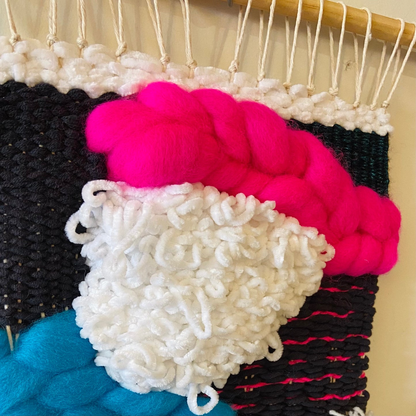 Close-up of colorful yarn on a loom with a neutral background