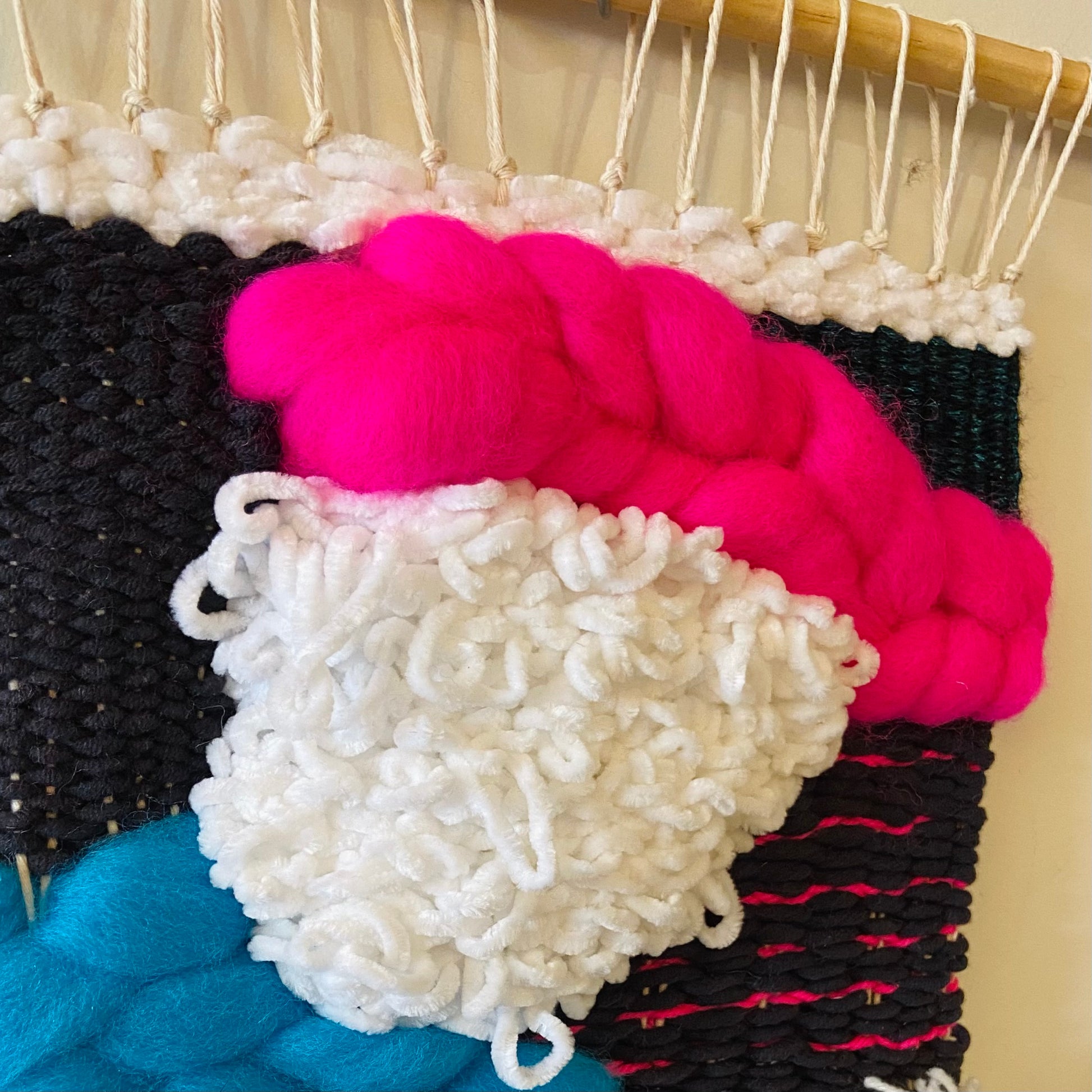 Close-up of colorful yarn on a loom with a neutral background