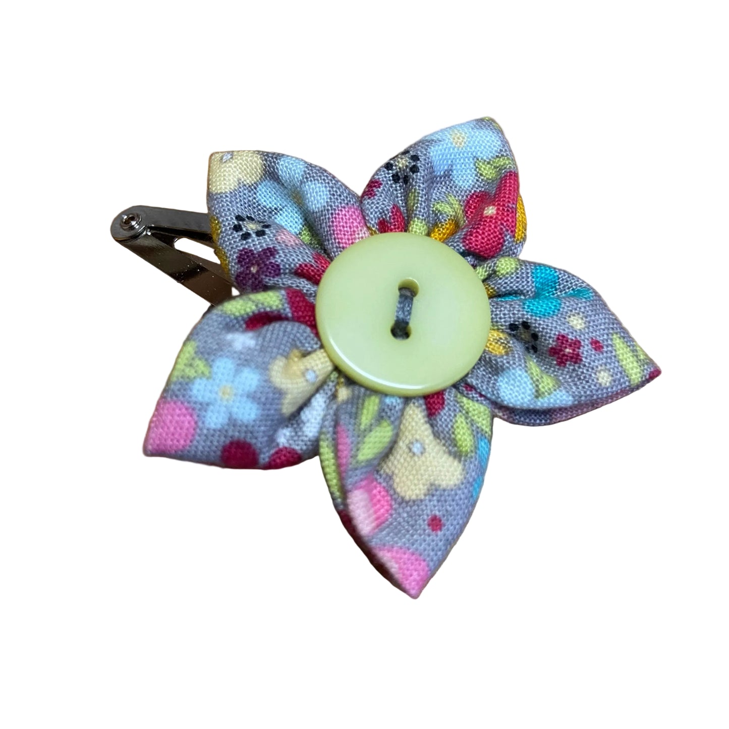 Colorful fabric flower hair clip with a button center on a wooden surface