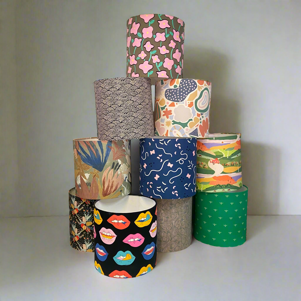 Stack of colorful patterned lampshades on a plain background