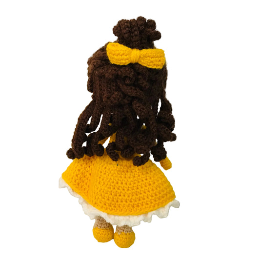 Crocheted doll with yellow dress and bow on a white background