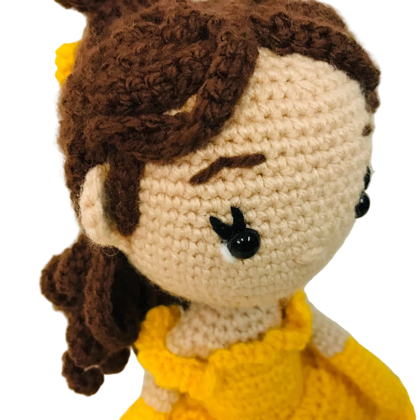 Crocheted doll with brown hair and a yellow dress on a white background