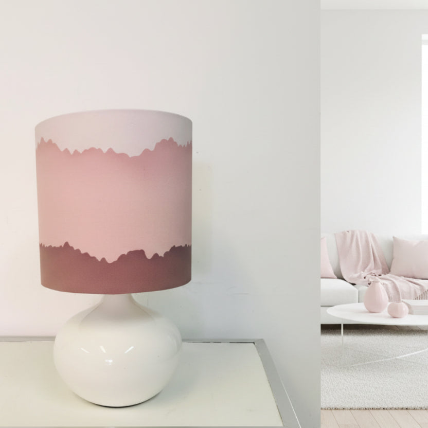 Lamp with a pink and white shade on a white base against a white background