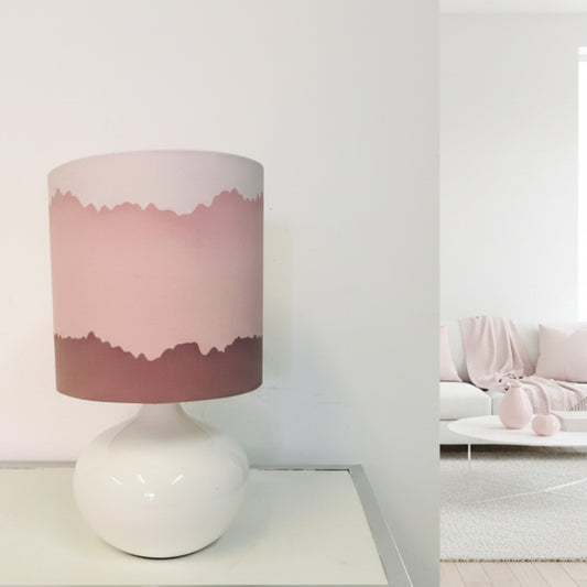 Lamp with a pink and white shade on a white base against a white background