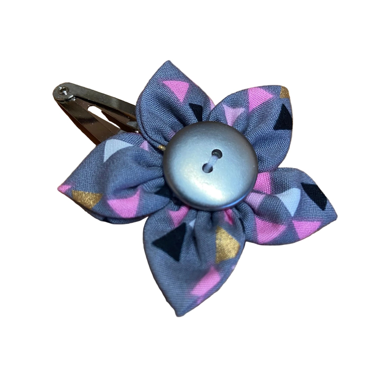 Decorative hair clip with geometric pattern and button center on a wooden surface