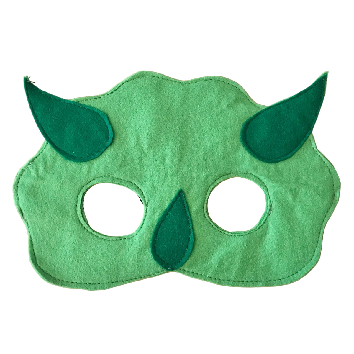 A green felt dinosaur mask with embroidered details and black elastic bands, displayed on a light wood background.