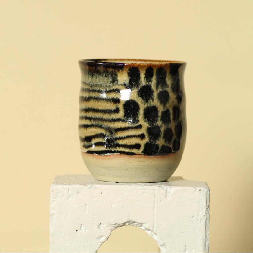 Ceramic cup with black abstract patterns on a beige background