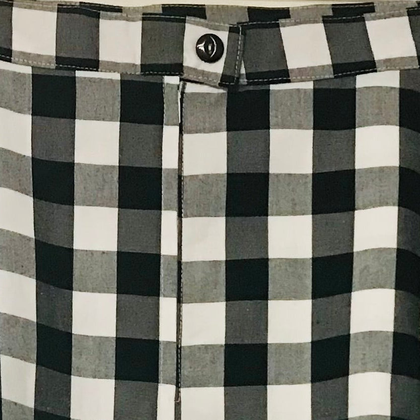 A black and white buffalo check A-line skirt hanging from a wooden hanger against a plain off-white wall.