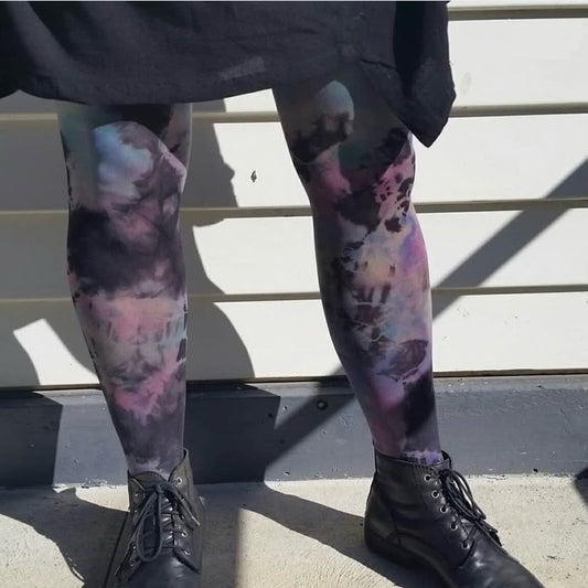 Person wearing colorful tie-dye leggings with black shoes