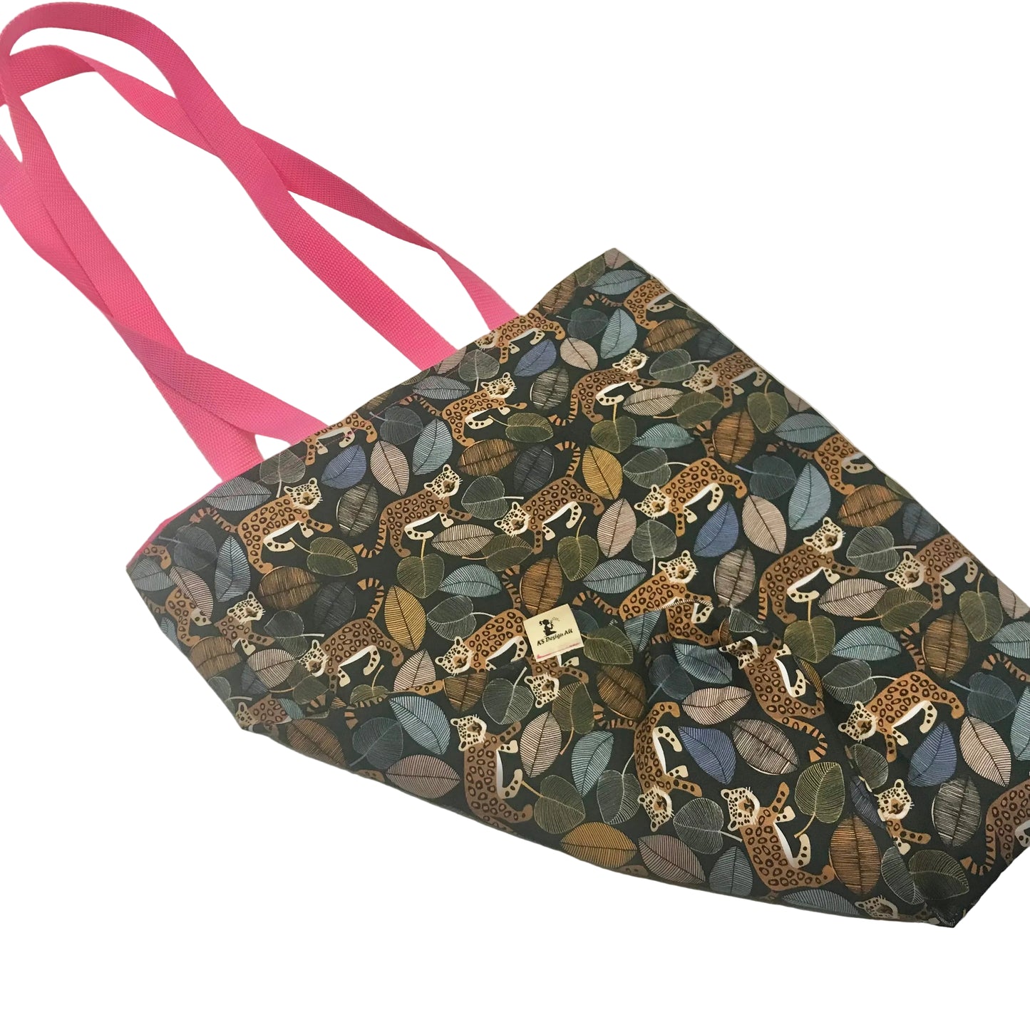 A fabric tote bag with a dark background covered in a pattern of leopards and leaves, featuring bright pink handles.