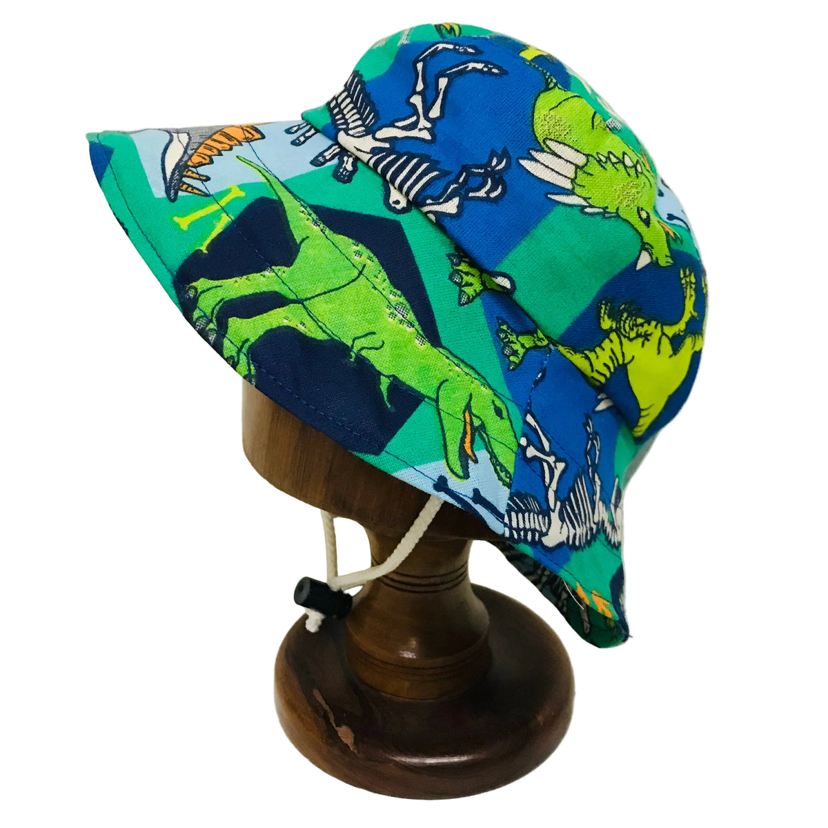 A children's wide-brim sun hat with a colorful dinosaur print, displayed on a wooden mannequin stand against a plain white background.