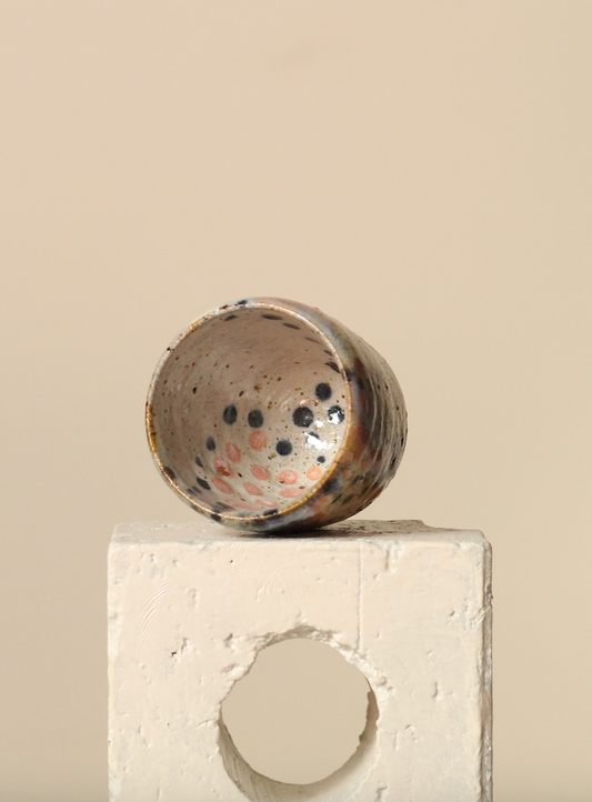 Ceramic espresso cup with speckled design on a beige surface