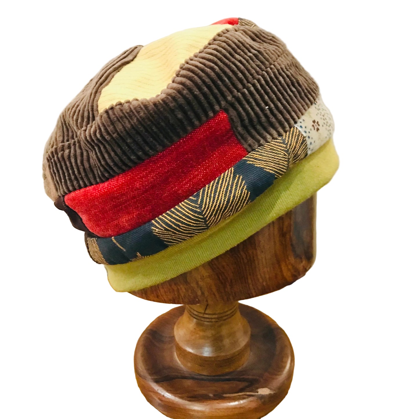 Colorful patchwork beanie on a wooden mannequin head against a neutral background