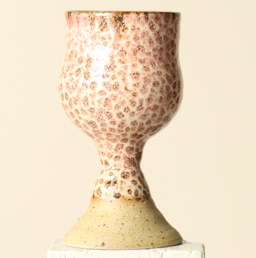Ceramic vase with speckled design on a beige background