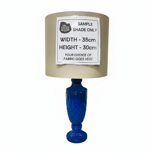 Lamp with blue base and beige shade on a white surface