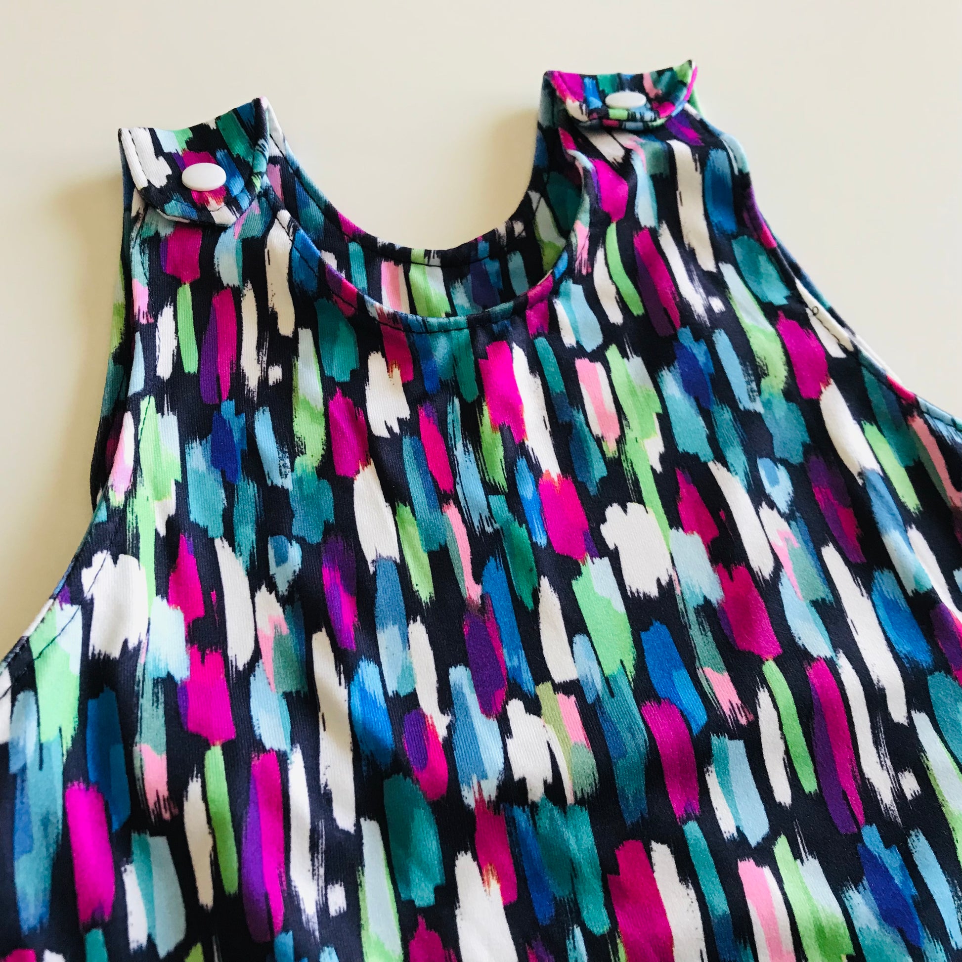Colorful sleeveless baby romper with abstract pattern on a plain background