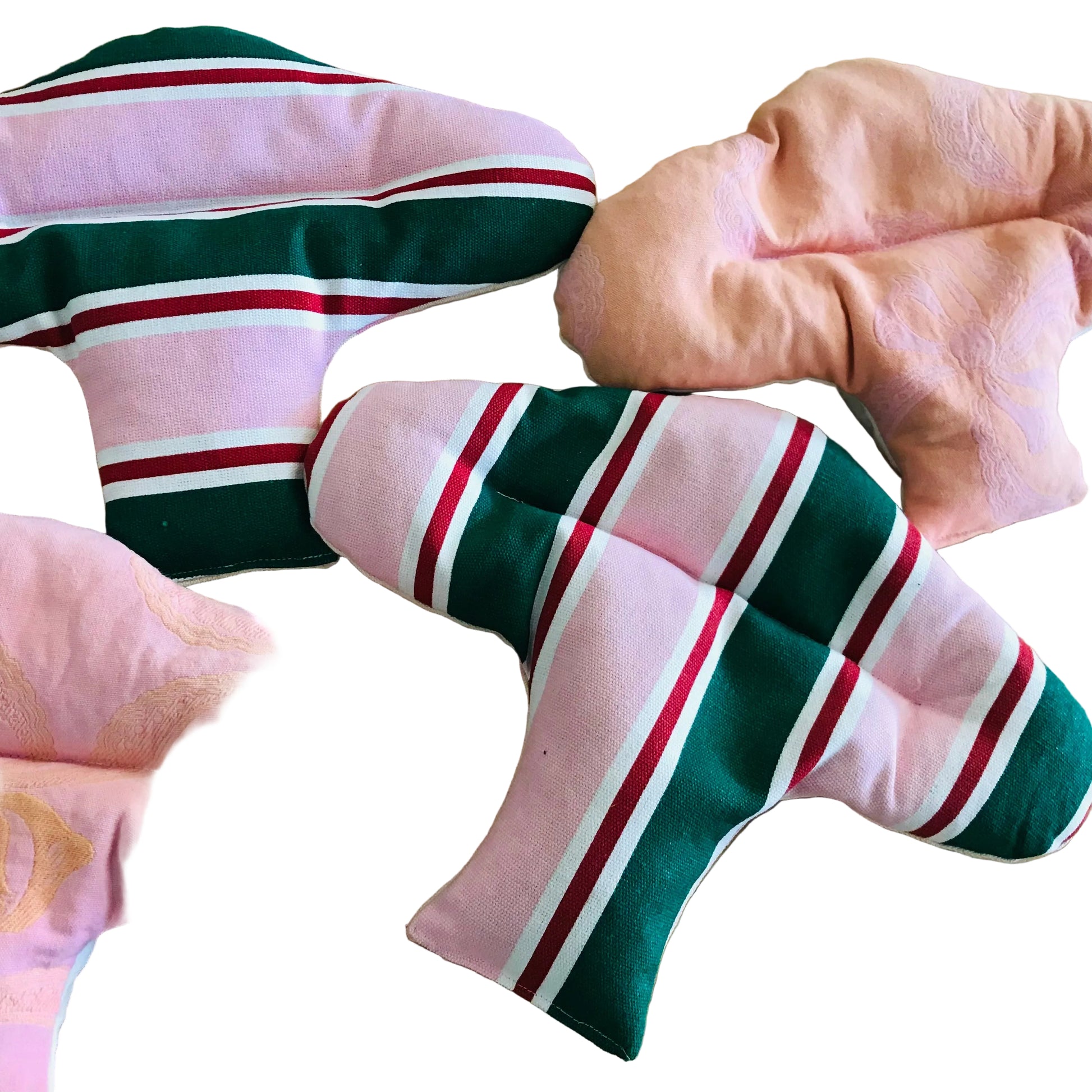 Four fabric menstrual pads arranged on a light wood surface. Two pads are light pink with gold floral embroidery, and two are pink with dark green, white, and red stripes.