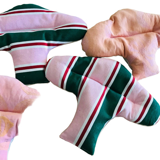 Four fabric menstrual pads arranged on a light wood surface. Two pads are light pink with gold floral embroidery, and two are pink with dark green, white, and red stripes.