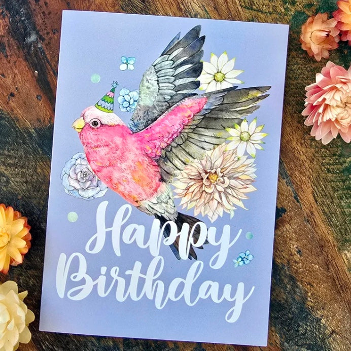 Birthday card with a galah and flowers on a wooden surface