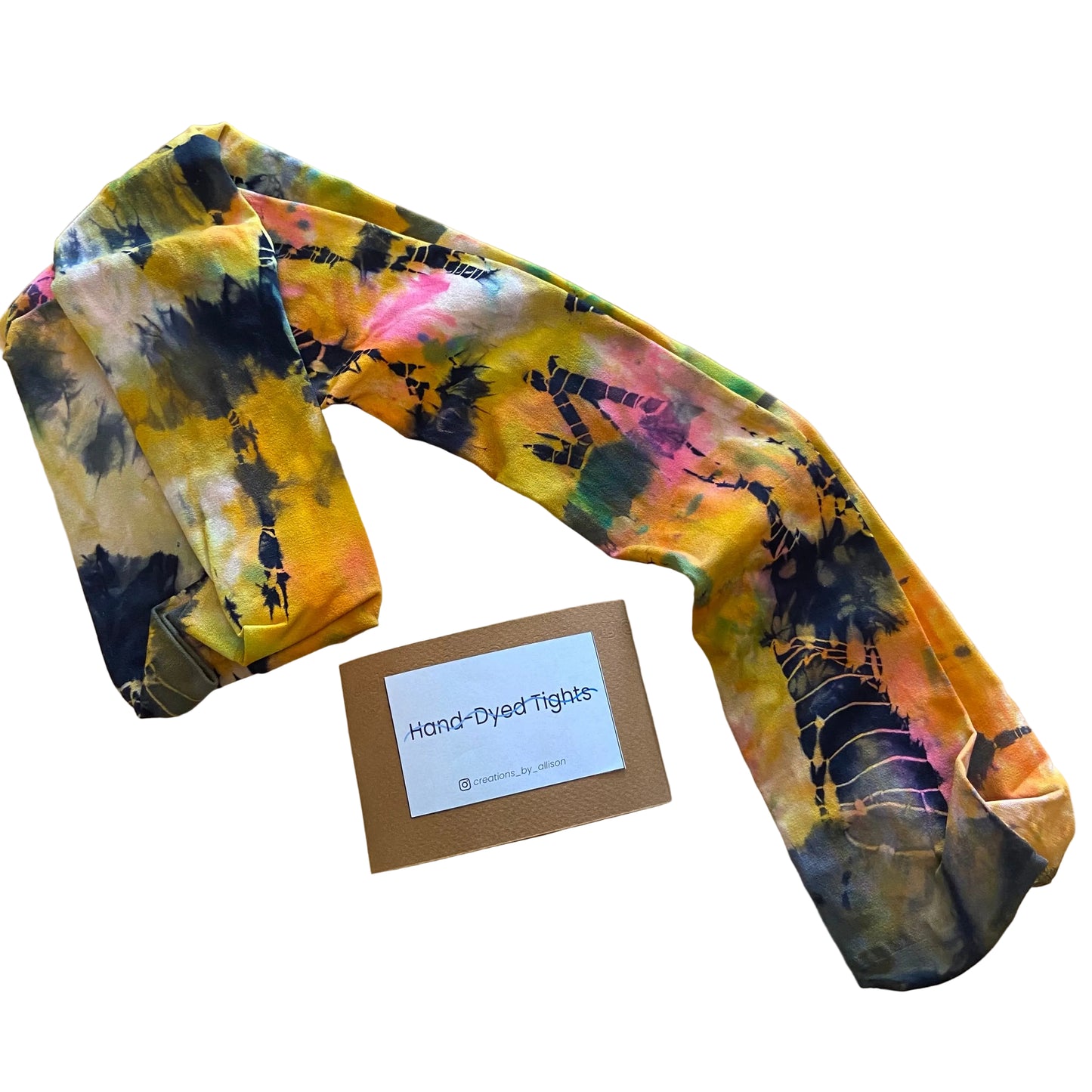 Colorful tie-dye tights on a wooden surface with a label indicating 'Hand-Dyed Tights'.