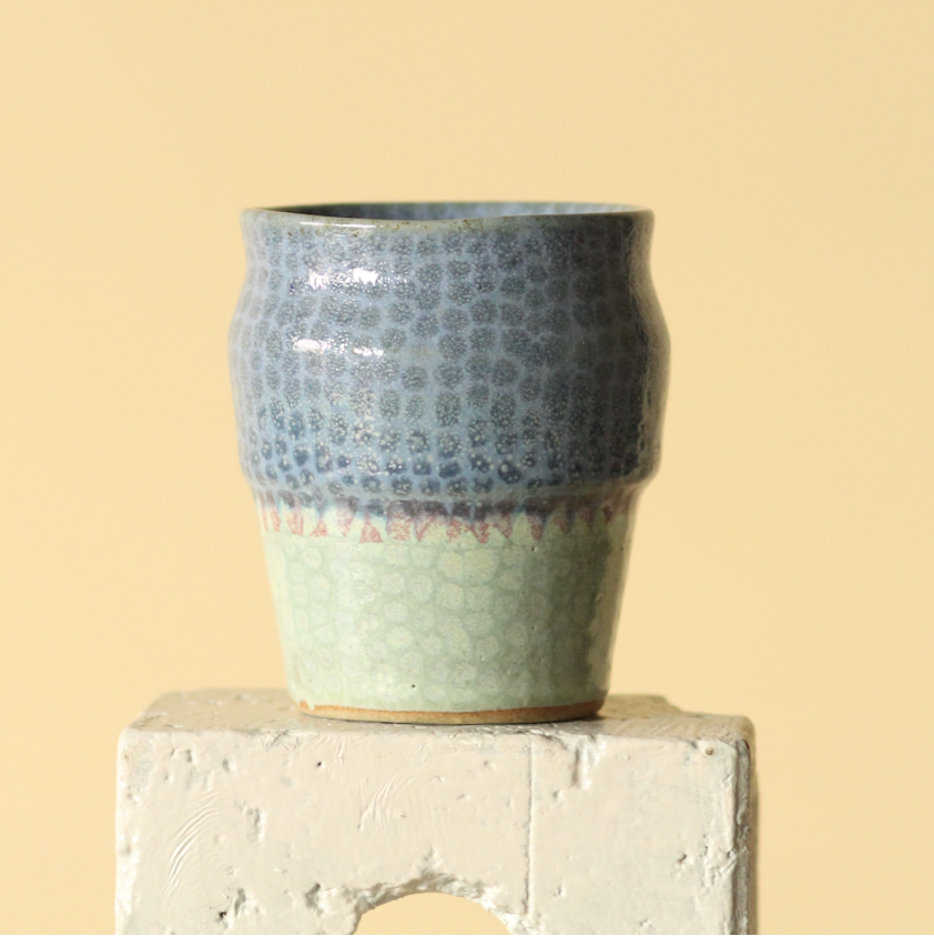 Ceramic cup with textured design on a beige background