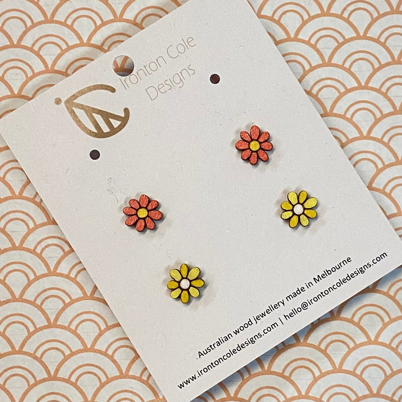 Flower-shaped earrings on a branded card with a patterned background