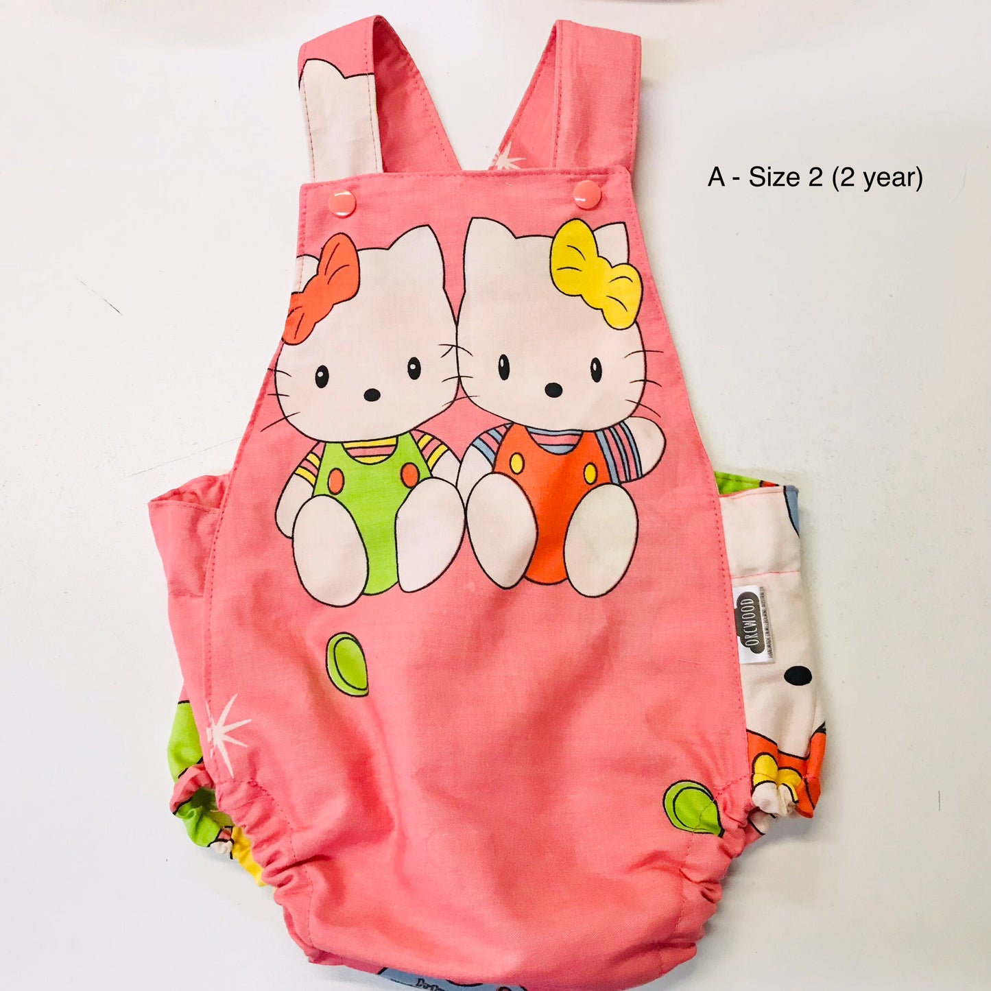 Pink children's romper with cartoon cat design on a white background