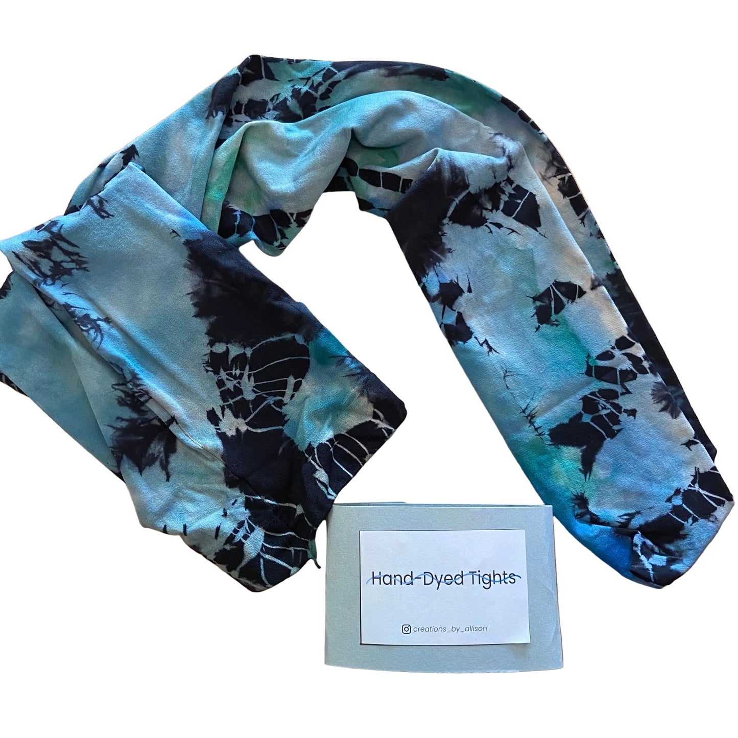 Hand-dyed tights with black and blue pattern on a wooden surface, accompanied by a label reading 'Hand-Dyed Tights'.
