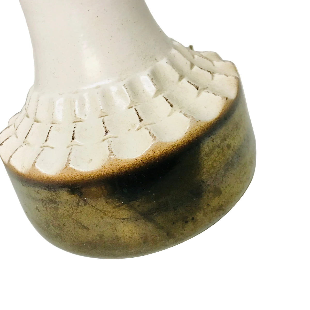 Close-up of a ceramic vase or bottle base with a glossy off-white upper section, a dark brown band, and a mottled olive-brown lower section on a light surface.
