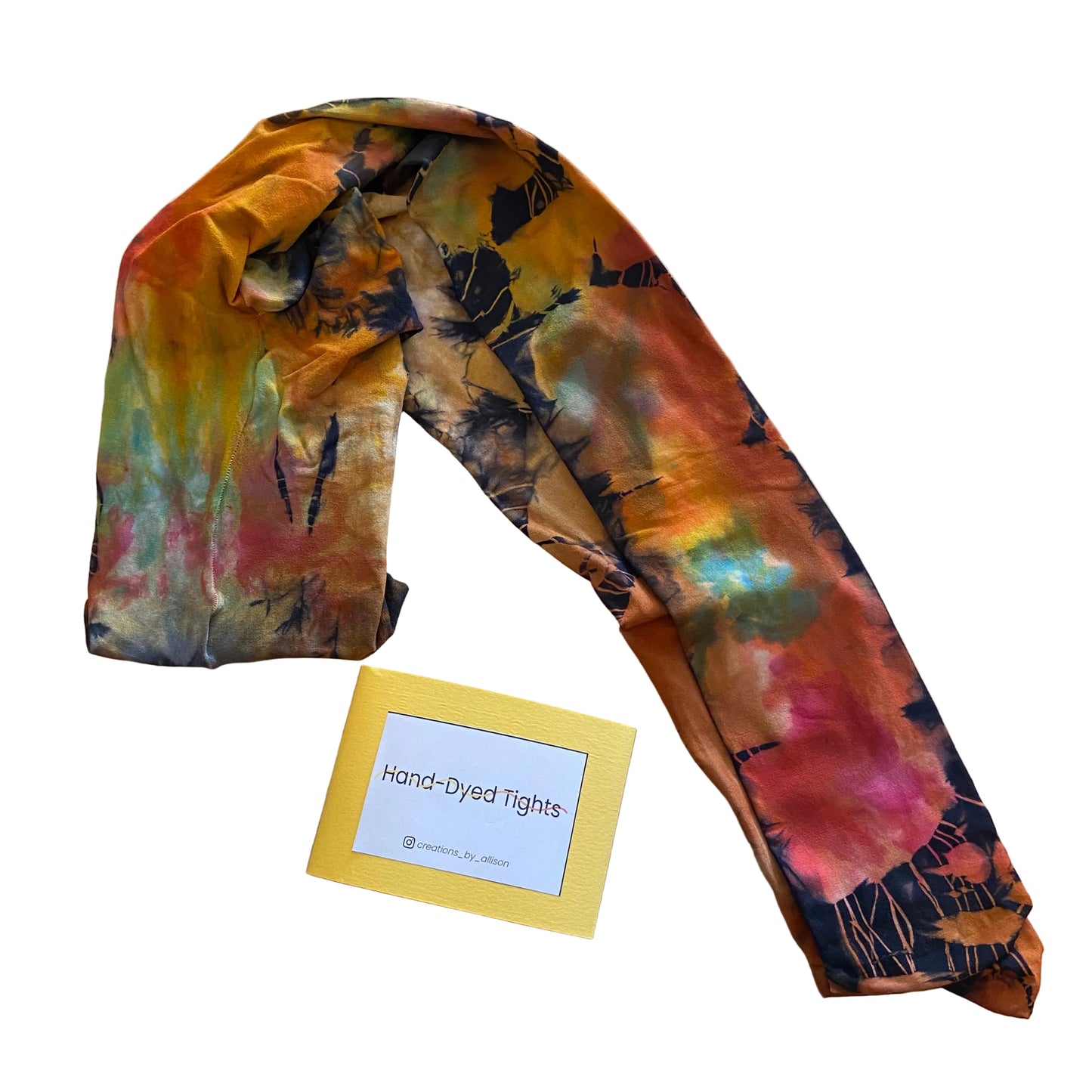 Hand-dyed tights with a colorful pattern on a wooden surface, accompanied by a label.