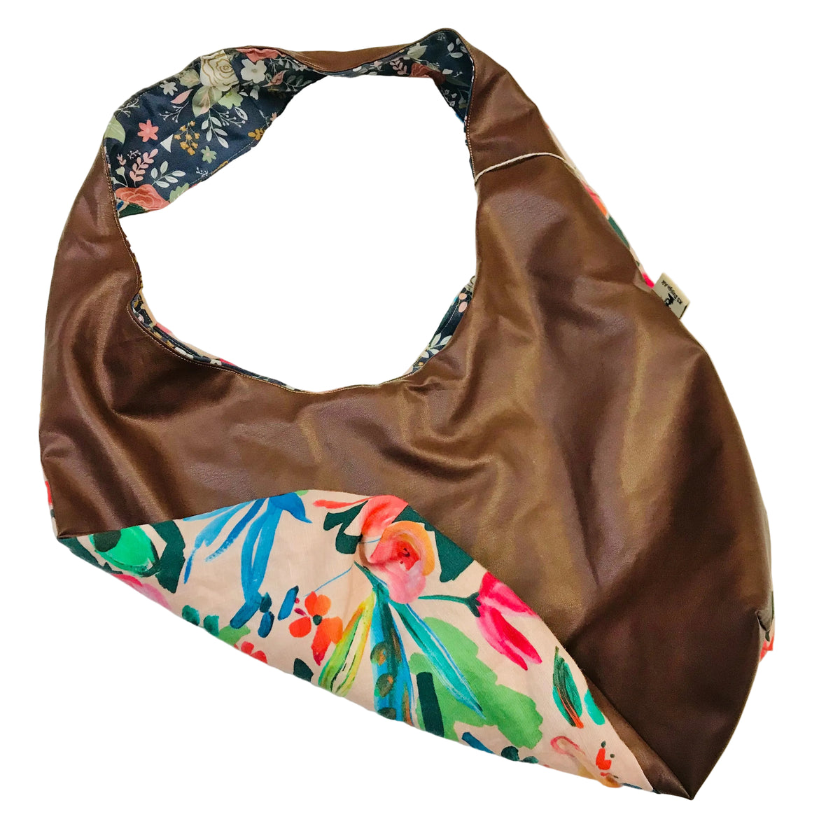 A brown faux-leather shoulder bag with a colorful floral print fabric trim and a dark navy floral patterned strap, displayed on a plain off-white background.